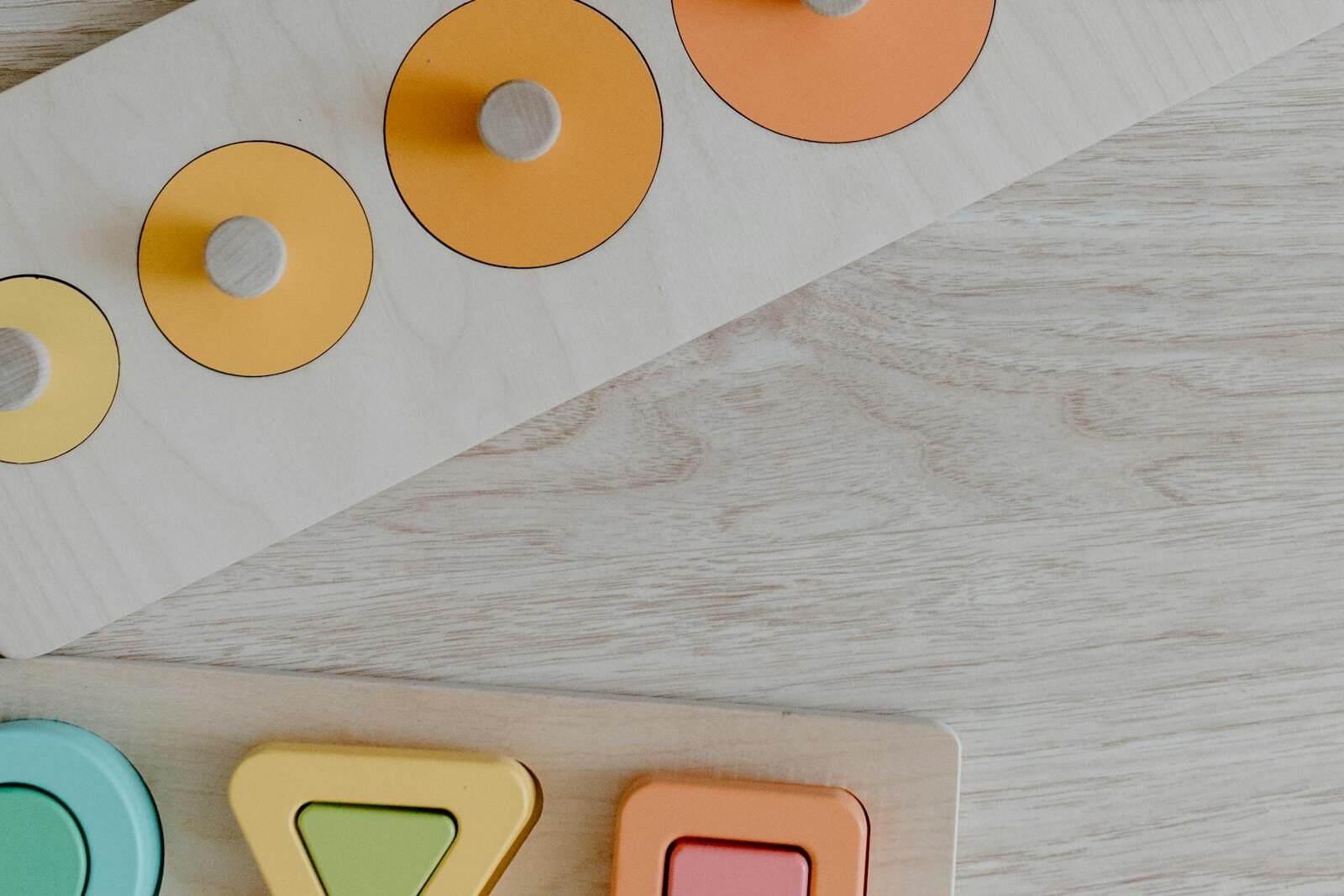 Colorful wooden puzzle pieces on a light wood surface, featuring geometric shapes for kids.